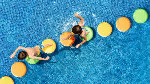 two children playing on lilypad-like steps in a pool