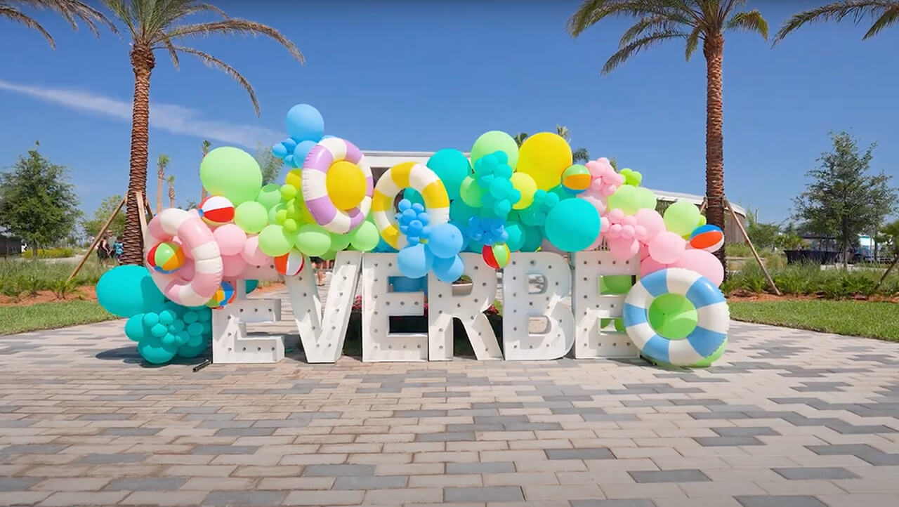 EverBe Amenity Center Event The Splashing Into Summer at EverBe in Orlando featured this sunny scene with a bright blue sky and palm trees in the background and giant white letters spelling EverBe crowned by a colorful balloon arch
